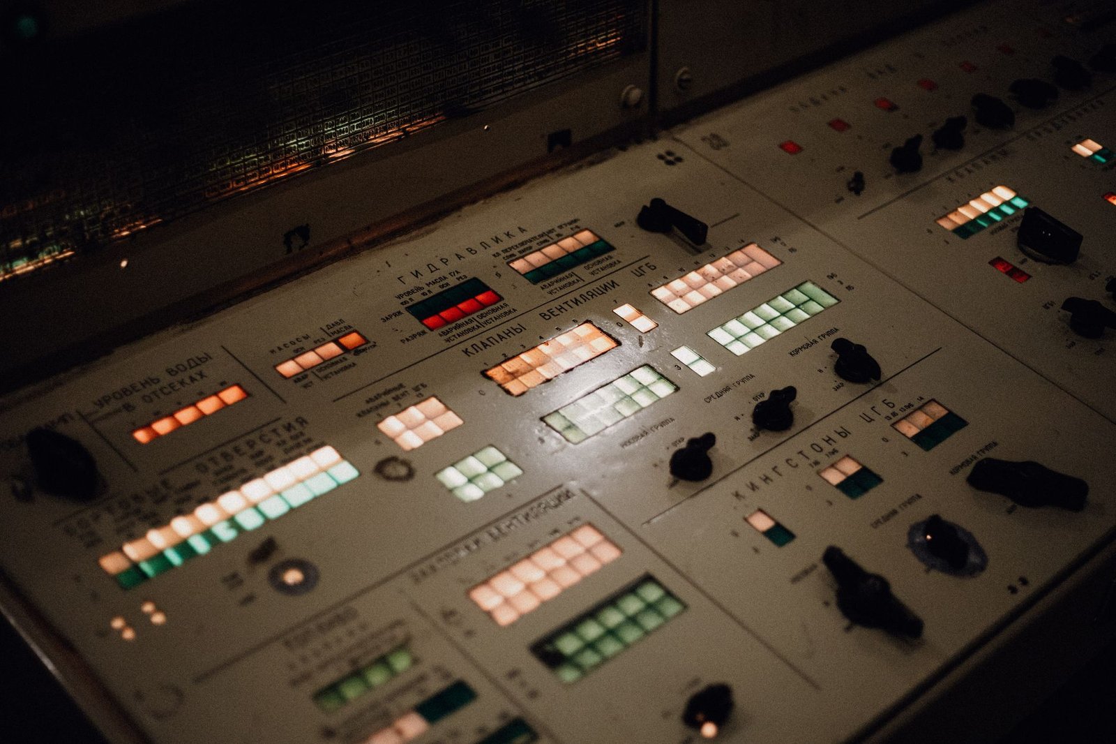 Close-up of an illuminated vintage control panel with various buttons and switches.
