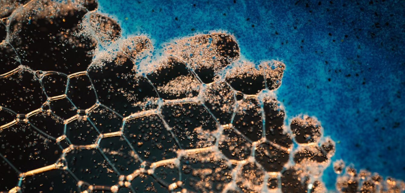 header-graphene-nanomaterial-closeup-19551958 Intricate close-up of soap bubbles creating abstract patterns on a blue background.