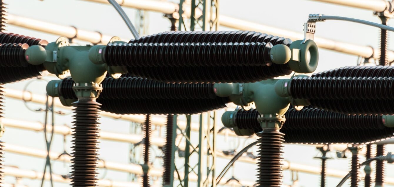 Close-up of outdoor electrical power equipment with insulators and conductors.