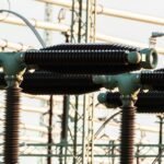 Close-up of outdoor electrical power equipment with insulators and conductors.
