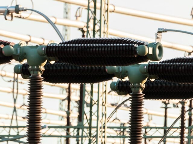 Close-up of outdoor electrical power equipment with insulators and conductors.