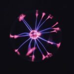 Transparent glass plasma ball with bright neon luminous against dark background in room