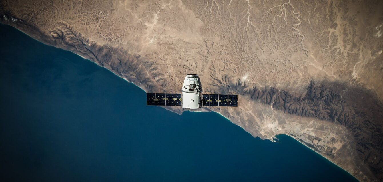 A satellite hovering above Earth's coastline, captured from space.