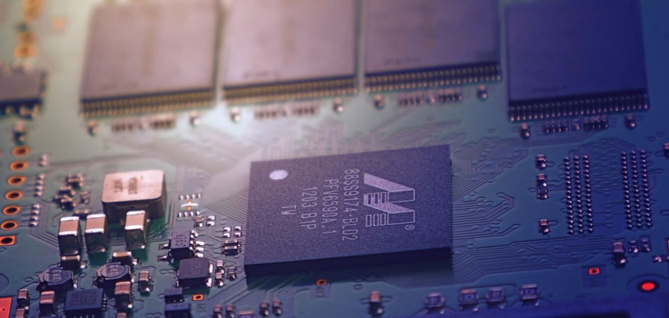 Detailed image of an electronic circuit board showing microchips and intricate wiring in a modern technological setting.