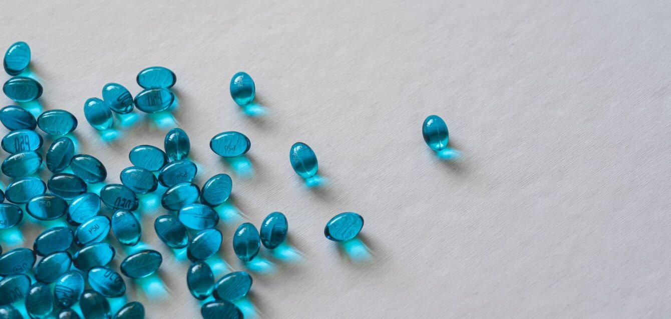 High angle view of scattered blue gel capsules on a flat white surface.
