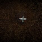 Top view of a vintage military aircraft abandoned in a field, showing decay.
