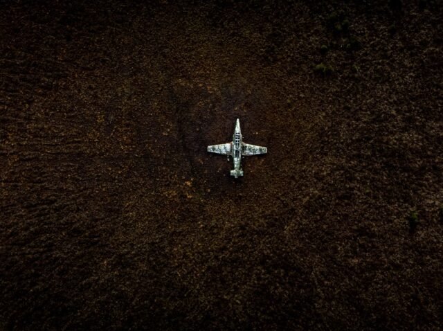 Top view of a vintage military aircraft abandoned in a field, showing decay.