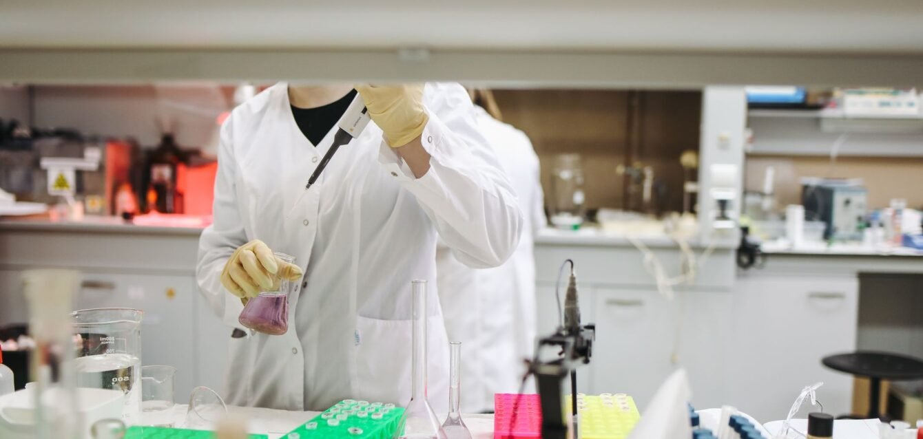 Scientist in a lab coat handling samples for scientific research in a modern laboratory setting.