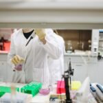 Scientist in a lab coat handling samples for scientific research in a modern laboratory setting.