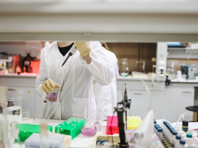 Scientist in a lab coat handling samples for scientific research in a modern laboratory setting.