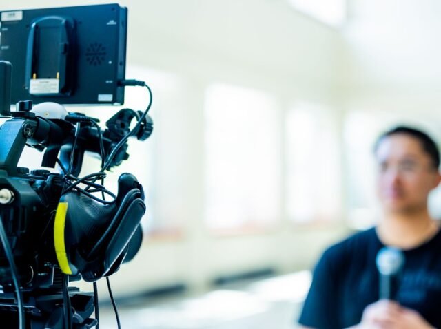 Professional video camera setup focusing on an interview with blurred subject in the background.